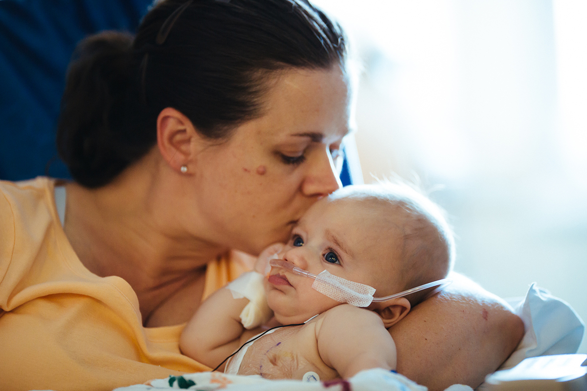 A mom kisses her infant, Children's National Health System Pediatric Cardiac Intensive Care Unit in Washington D C.