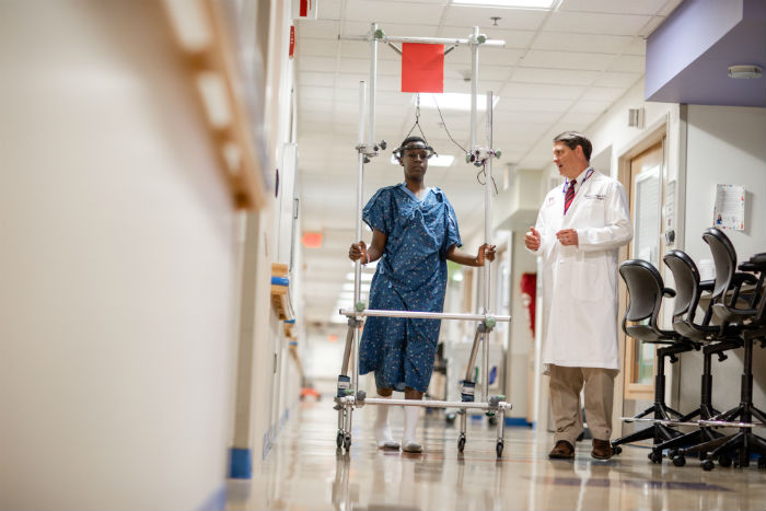 Orthopaedic surgeon and male patient walking in hallway