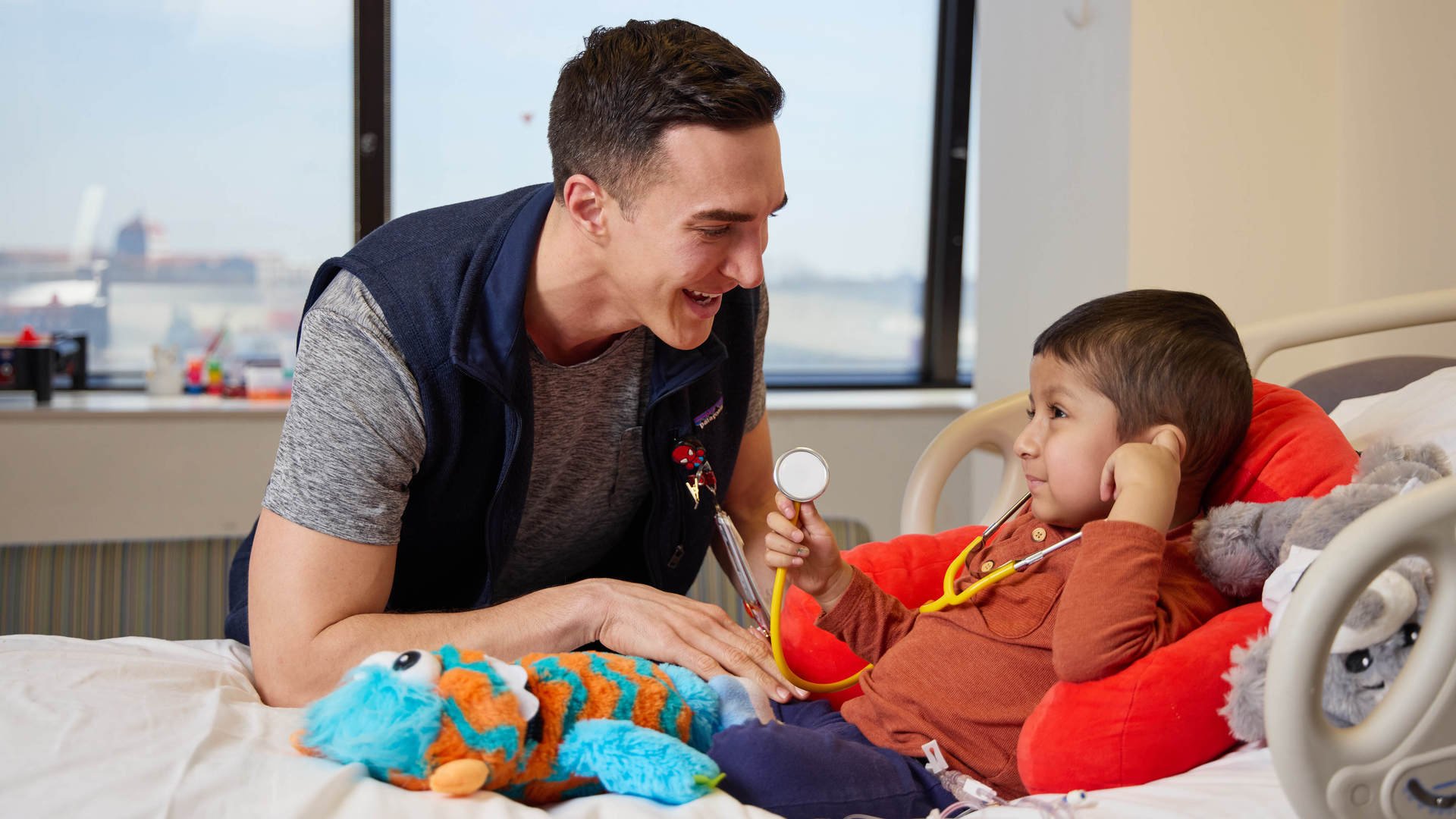 a nurse smiling and interacting with a young patient in a hospital bed