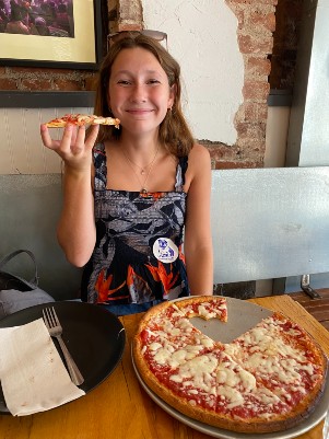 Maia smiling about to eat some pizza