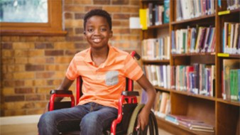 boy in wheelchair in front of bookshelf