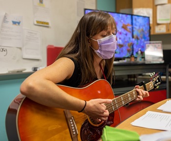 A music therapist plays guitar in the comfort corner.