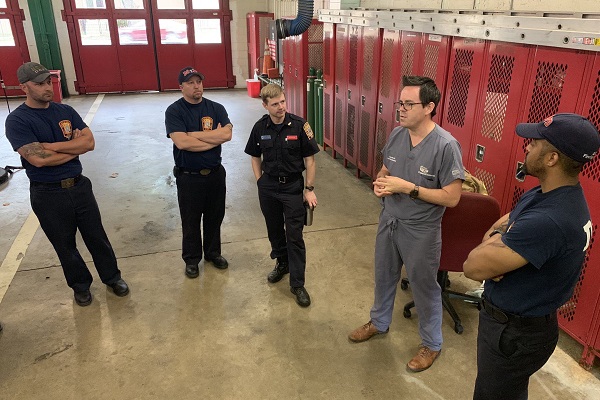 A male Children's National Emergency Department team member talks with emergency health care providers in a fire station in the District of Columbia.
