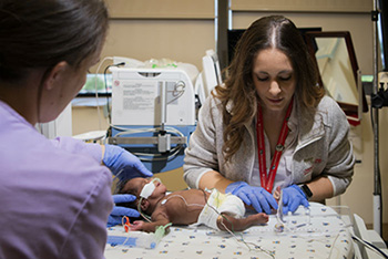 two nurses working with a baby
