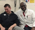 Jacob Yates, an 18-year-old patient, and Dr. Chima Oluigbo sit together at Children's National Hospital.