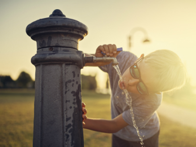 boy drinking from public water fountain