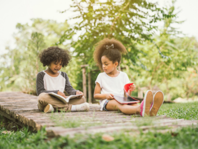 two kids reading books outside