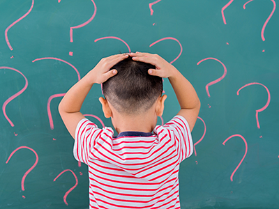 boy in front of board with question marks