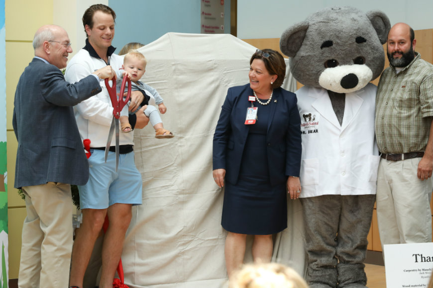john carlson holds child with dr. bear, kathy gorman and kurt newman smiling nearby