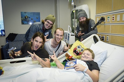Members of a musical group hang out at a boy's hospital bedside
